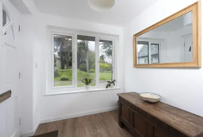 a white room with a window and a wooden dresser at 3 Menague in Padstow