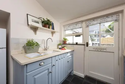 a kitchen with blue cabinets and a sink at Aloe Cottage in Padstow