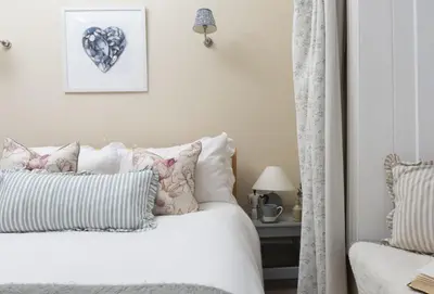 a bedroom with a white bed with pillows at Aloe Cottage in Padstow