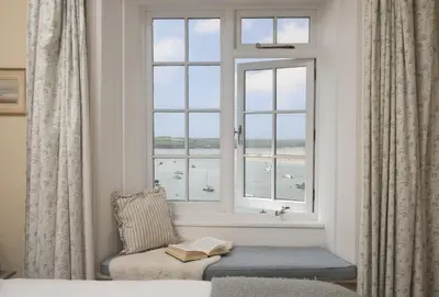 a room with a window with a chair and a book at Aloe Cottage in Padstow