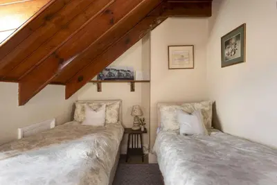 two beds in a room with wooden ceilings at Aloe Cottage in Padstow