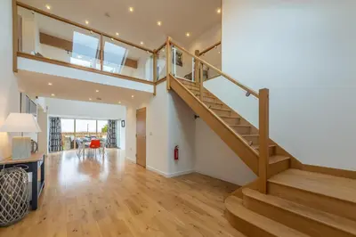 a staircase in a living room with wooden floors at Highcroft in Saint Minver