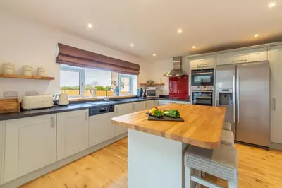 a kitchen with white cabinets and a wooden counter top at Highcroft in Saint Minver
