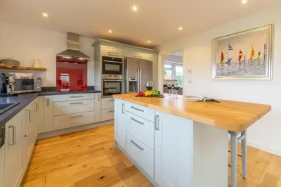 a kitchen with white cabinets and a wooden counter top at Highcroft in Saint Minver