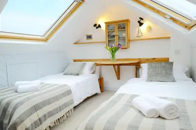 two beds in a room with a table and a window at 4 Victoria House with the best views in St Ives in St Ives