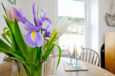 a vase filled with purple and white flowers on a table at 4 Victoria House with the best views in St Ives in St Ives