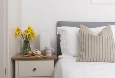 a bed with a vase of flowers on a night stand at Bluebirds in Polzeath