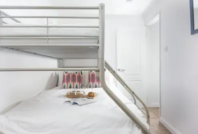 a bedroom with a bunk bed with white walls at Bluebirds in Polzeath