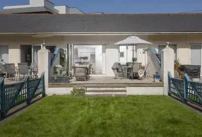 a house with a patio with chairs and an umbrella at Bluebirds in Polzeath