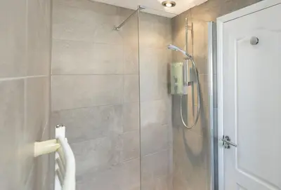 a bathroom with a shower with a glass door at Bluebirds in Polzeath