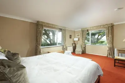 a bedroom with a large white bed and two windows at Rabbit Hill in Polzeath