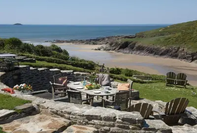 a patio with a table and chairs and a beach at Rockside Studio in Polzeath