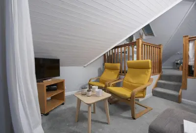 a living room with two chairs and a television at Rockside Studio in Polzeath