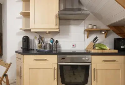 a kitchen with wooden cabinets and a stove top oven at Rockside Studio in Polzeath