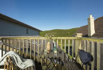 a patio with a table and chairs on a deck at Rockside Studio in Polzeath