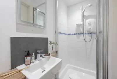 a white bathroom with a sink and a shower at Rockside Studio in Polzeath