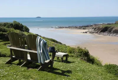 two chairs sitting on a hill next to a beach at Rockside Studio in Polzeath