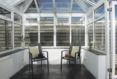a greenhouse with two chairs in the middle at Tresevens in Polzeath