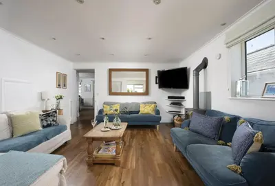 a living room with blue couches and a tv at Tresevens in Polzeath