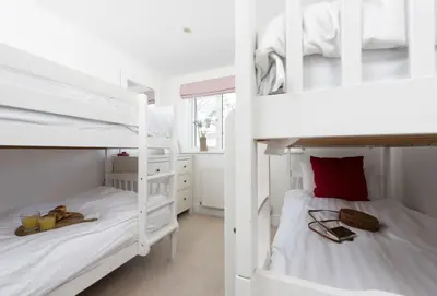 two bunk beds in a room with white walls at Tresevens in Polzeath
