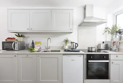 a white kitchen with white cabinets and a sink at Robin in Polzeath