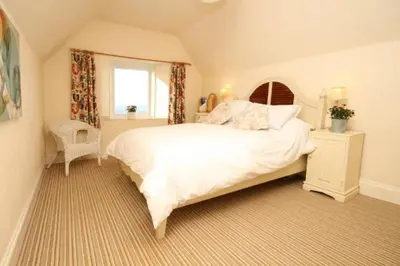 a bedroom with a large white bed and a window at Trevose View in Polzeath