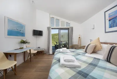 a bedroom with a bed and a desk and a window at The Perch Studio in Polzeath