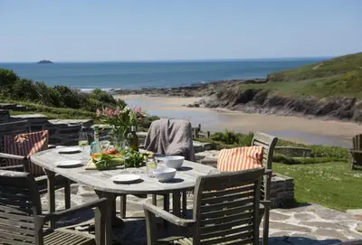 a table with chairs and a view of the beach at The Perch Studio in Polzeath