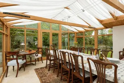 a conservatory with a table and chairs and windows at Trerair in Saint Minver