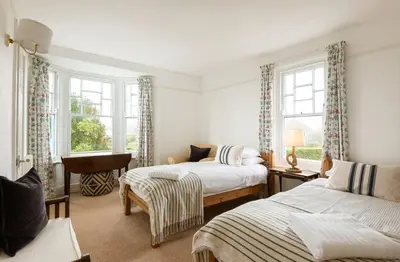 a bedroom with two beds and two windows at Trerair in Saint Minver
