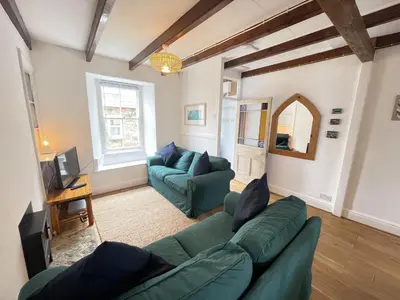 a living room with two green couches and a tv at Silver Seahorse a classic fishermans cottage in St Ives