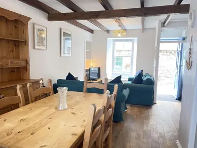 a living room with a table and a blue couch at Silver Seahorse a classic fishermans cottage in St Ives