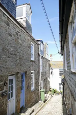 an alley with stone buildings and a blue door at Silver Seahorse a classic fishermans cottage in St Ives