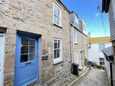 a stone house with a blue door on a street at Silver Seahorse a classic fishermans cottage in St Ives