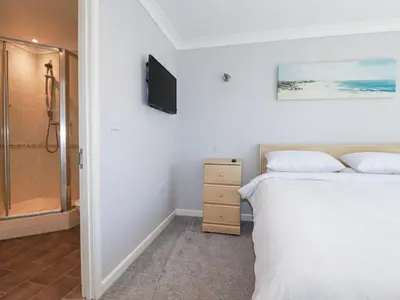a bedroom with two beds and a television on the wall at Satinwood in Newquay