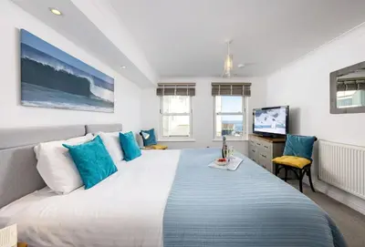 a bedroom with a large bed with blue pillows at 8 Spinnakers in Fistral, Newquay in Newquay