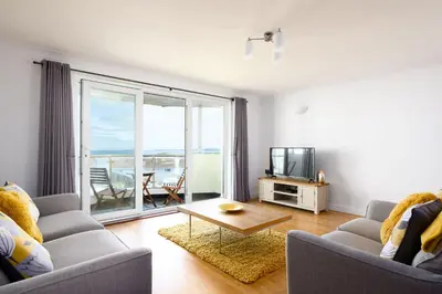 a living room with a couch and a tv at 8 Spinnakers in Fistral, Newquay in Newquay