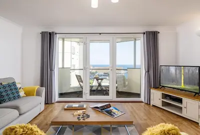 a living room with a couch and a tv at 8 Spinnakers in Fistral, Newquay in Newquay