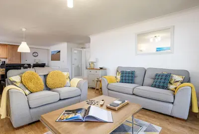 a living room with two couches and a table at 8 Spinnakers in Fistral, Newquay in Newquay