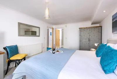 a bedroom with a large white bed with blue pillows at 8 Spinnakers in Fistral, Newquay in Newquay