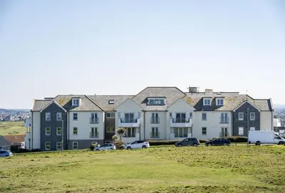a row of houses with cars parked in a field at 8 Spinnakers in Fistral, Newquay in Newquay