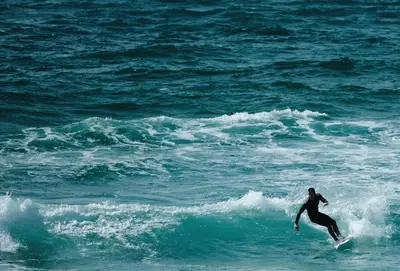 a person riding a wave on a surfboard in the ocean at 8 Spinnakers in Fistral, Newquay in Newquay