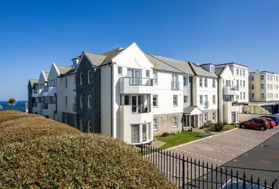 a row of apartment buildings with a parking lot at 8 Spinnakers in Fistral, Newquay in Newquay