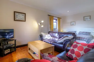 a living room with a leather couch and a tv at Shilbury Retreat Cottage near Perranporth in Perranporth