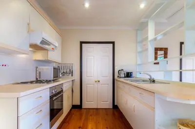 a kitchen with white counters and a white door at Shilbury Retreat Cottage near Perranporth in Perranporth