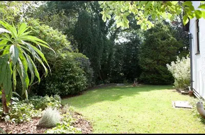 a garden with a yard with green grass and trees at Shilbury Retreat Cottage near Perranporth in Perranporth