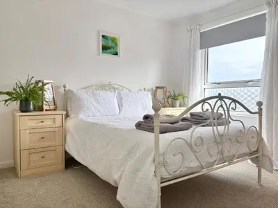 a bedroom with a white bed and a window at Falmouth Oasis with sub-tropical garden & parking in Falmouth
