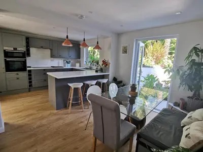 a kitchen and living room with a table and chairs at Falmouth Oasis with sub-tropical garden & parking in Falmouth