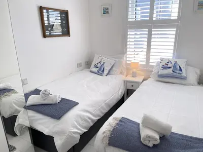 two twin beds in a room with a mirror at 4 Hazelbury House - a tranquil hidden gem in St Ives