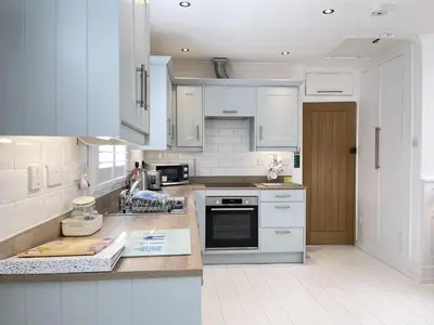 a kitchen with white cabinets and a counter top at 4 Hazelbury House - a tranquil hidden gem in St Ives